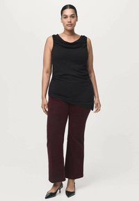 Top negro sin mangas con escote drapeado, combinado con pantalones de pierna amplia burdeos y zapatos de tacón negro. Textura de tela suave.
