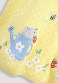 Keltainen pilkullinen kangas, jossa on brodeerattu hiiri sinisessä kastelukannussa, mansikka ja kukat valkoisina ja vaaleanpunaisina. Pehmeä rakenne, leikkisä muotoilu.