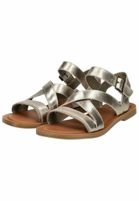 Sandali strappy argento metallizzato con suola piatta color nocciola, caratterizzati da cinturini incrociati e una fibbia regolabile per la chiusura.