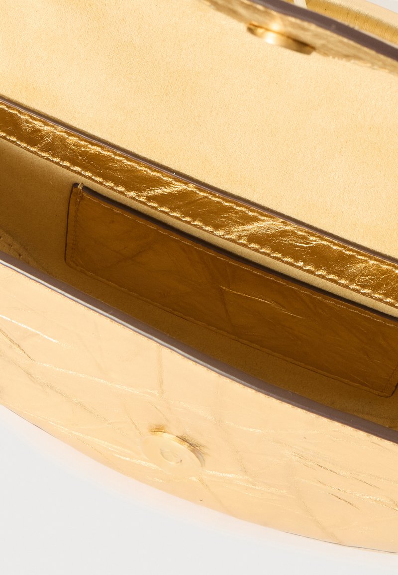 Goldfarbener Innenteil der Handtasche mit einer glatten Lederinnenausstattung, ausgestattet mit einer flachen Tasche und einem Druckverschluss für sichere Aufbewahrung.