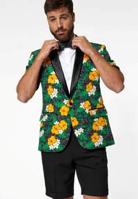 Květinový blazer s žlutými a bílými květy na zeleno-černém pozadí, s černým saténovým límcem, spojený s černými šortkami.