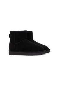 Botas de tobillo de ante negro con punta redonda, parte superior texturizada, suela de goma plana y un pequeño tacón. Presentan una pestaña en la parte trasera y acentos cosidos.