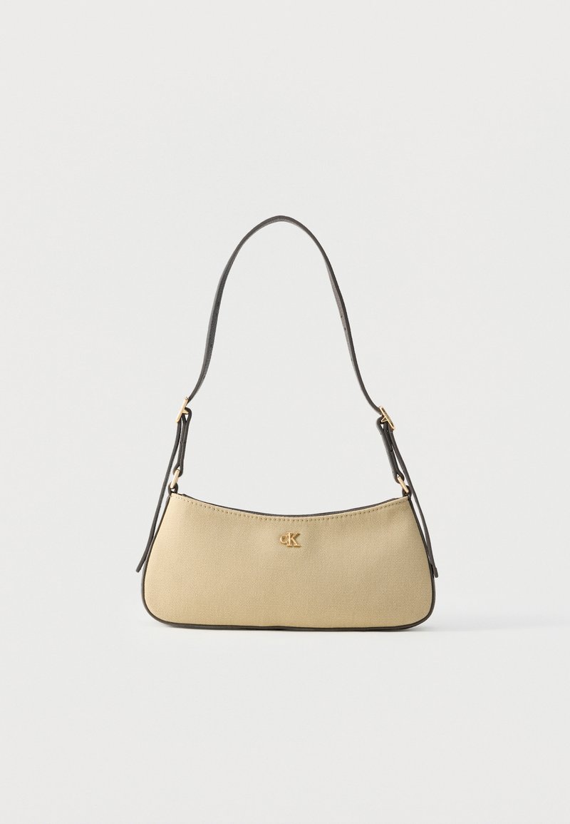 Sac à main beige pour épaule avec sangle noire ajustable et petit logo doré « cK » centré sur le panneau avant.