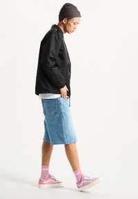 Black lightweight jacket, light blue denim shorts, pink sneakers with white accents, wearing pink socks. Beanie hat adds texture.