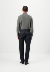 Gray long-sleeve shirt, dark blue denim pants, five-pocket design, tonal stitching, and black leather shoes viewed from the back.