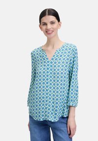 Blauw en groen gebloemde blouse met een V-hals, driekwart mouwen en lichte stof. Het ontwerp heeft een geometrisch motief.