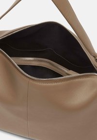 Brązowa skórzana torebka o gładkiej teksturze, z zapinaniem na zamek i czarną tkaniną w środku. Posiada wewnętrzne kieszenie do organizacji.