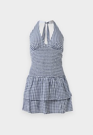 Rutete solkjole i marineblått og hvitt, med en tettsittende overdeler, halterneck, åpen rygg og volanger i tiered hem.