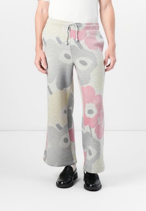 Un pantalon de survêtement à motif floral en gris clair, avec de grandes fleurs roses et grises, doté d'une taille élastique et d'un cordon de serrage.