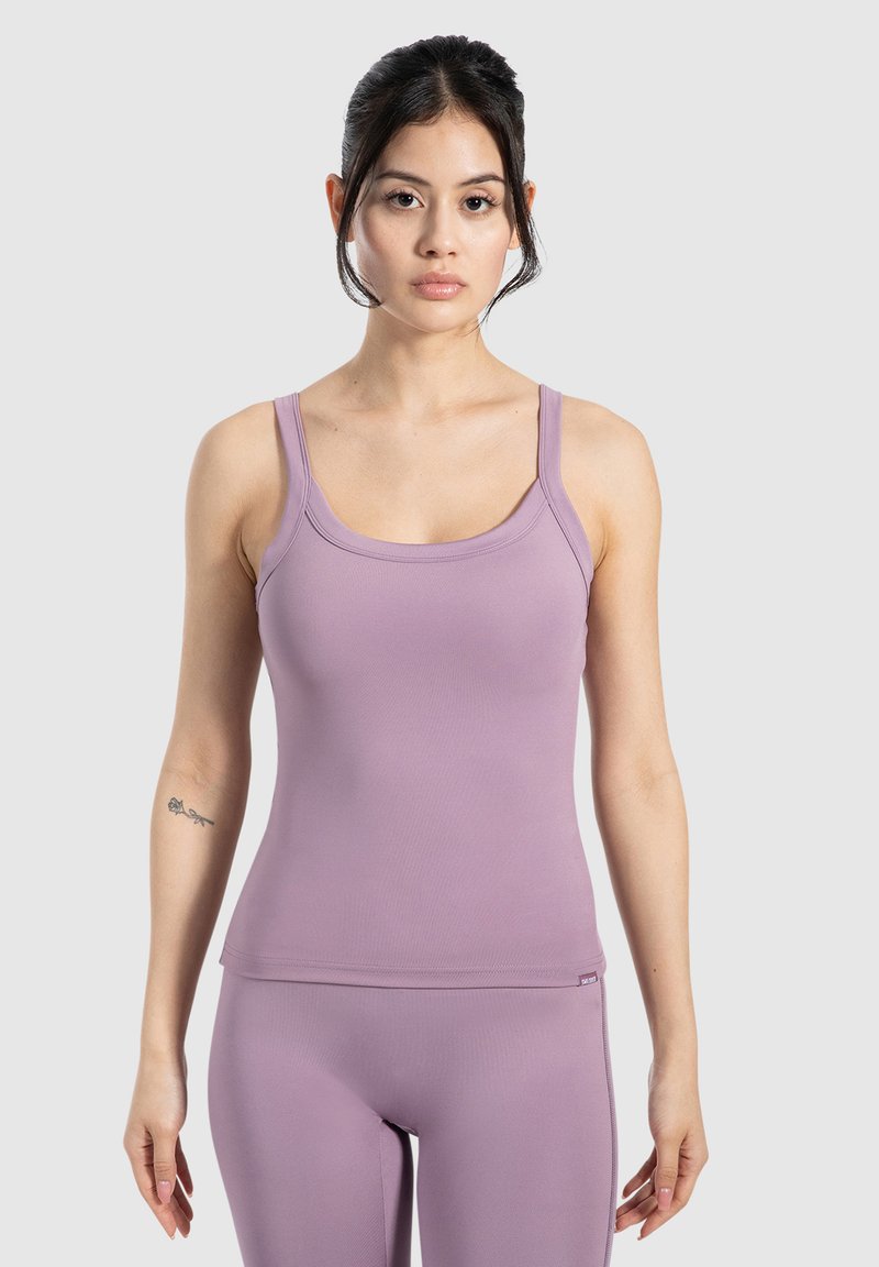 Top a canottiera lilla con spalline sottili, scollatura rotonda, design aderente e texture elastica, abbinato a leggings aderenti coordinati.