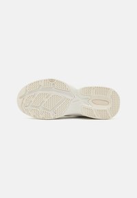 Sko såle med teksturert gummimateriale, med et bølgete mønster og støttegrøfter, hovedsakelig i off-white med en lysere aksent.