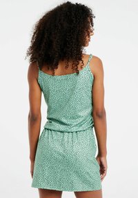 Groene polkadot mouwloze jurk met een losse pasvorm, een gerimpelde taille en een gladde textuur. Voorzien van dunne bandjes en een uitlopende rok.