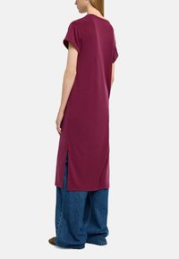 Bordowa, oversize sukienka t-shirtowa z krótkimi rękawami, z bocznymi rozcięciami i luźnym krojem, wykonana z miękkiego, oddychającego materiału.
