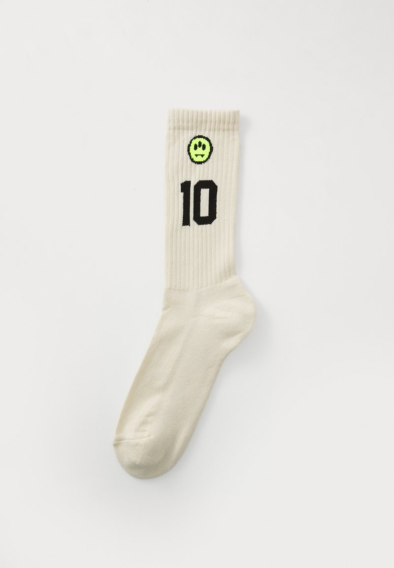 Chaussettes côtelées de couleur crème avec un "10" noir et un visage souriant vert sur le revers. Tissu doux et extensible.