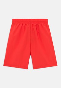 Røde treningsshorts laget av lett materiale, med elastisk midjebånd og glatt tekstur. Ingen synlige mønstre eller detaljer.