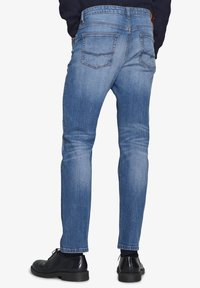 Jasnoniebieskie dżinsy o slim fit, z tylnymi kieszeniami, paskiem w pasie i gładką, czystą teksturą.