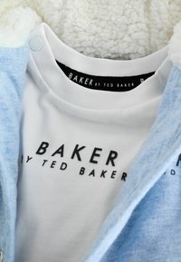 Felpa azzurra chiara sovrapposta a una maglietta bianca. La maglietta presenta un testo nero con la scritta "BAKER by TED BAKER" sul collo.