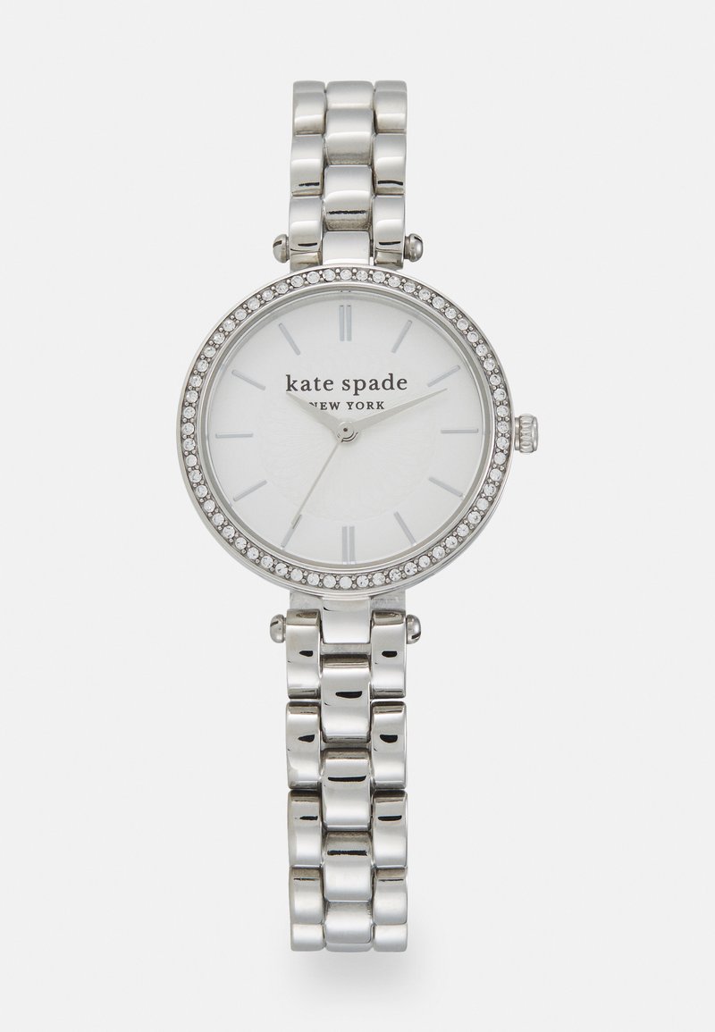 Orologio argento con quadrante rotondo, dotato di un dial bianco, indicatori delle ore argentati e una lunetta adornata di cristalli. Bracciale a maglie in metallo.