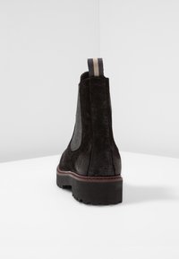 Stivale Chelsea in suede nero con corpo texturizzato, pannelli laterali elasticizzati e una linguetta grigia a contrasto. Suola in gomma nera spessa con motivo battistrada.
