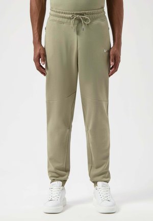 Lichtgroene joggers met een trekkoord in de taille, taps toelopende benen en zijzakken, gecombineerd met witte sneakers.
