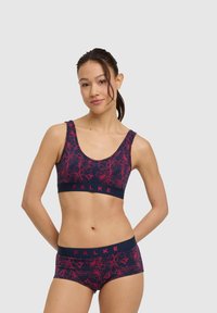 Granatowy zestaw sportowy: biustonosz i szorty z różowym kwiatowym wzorem. Miękka tkanina, szerokie ramiączka oraz elastyczna opaska z logo "FALKE".