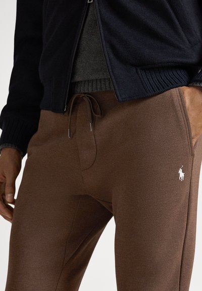 Brązowe spodnie dresowe z sznurkiem w pasie, gładką fakturą i małym białym logo konia na lewej udzie.