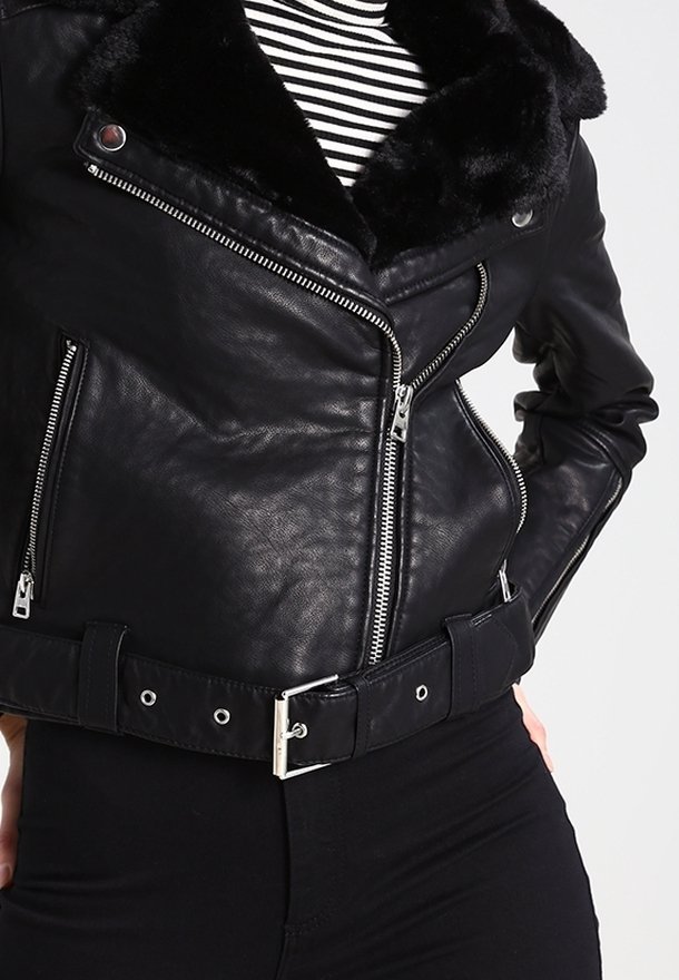 Černá kožená motorkářská bunda s límcem z umělé kožešiny, stříbrnými zipy a širokým páskem v pase. Má přiléhavý střih a žebrovanou texturu.