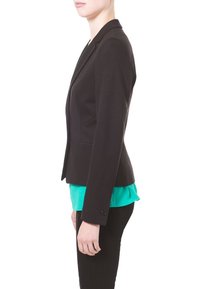 Schwarzer Blazer mit schmaler Passform, zwei Knöpfen und strukturierten Schultern, über einer türkisfarbenen Bluse getragen, kombiniert mit schwarzen Hosen.