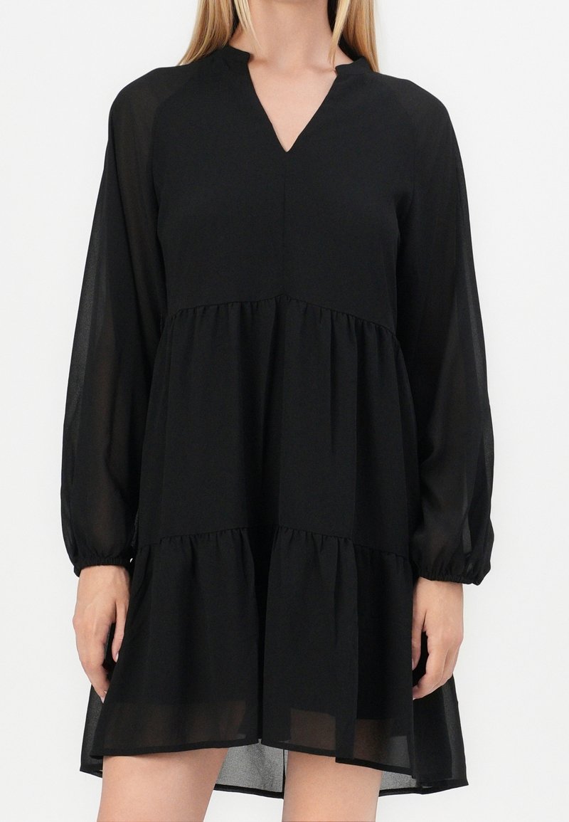 Robe noire en tissu léger et transparent avec des manches longues bouffantes, un col en V et un ourlet à volants à étages. Design simple et fluide.