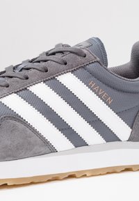 Grey sneaker with white stripes, suede and mesh materials, gum sole, and "HAVEN" label on the side.