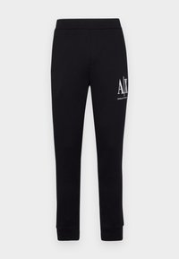 Svarta sweatpants med elastisk midja och muddar, med en vit logotyp på vänster ben. Tillverkade av mjukt, stretchigt material.