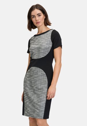 Schwarzes Kleid mit kurzen Ärmeln, das ein strukturiertes graues Panel über der Brust und eine größere graue Akzentuierung an der unteren Seite aufweist.