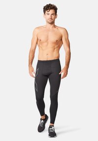 Sorte kompressions leggings med en glat tekstur, prydet med et gråt vinklet mønster på låret og en tætsiddende pasform.