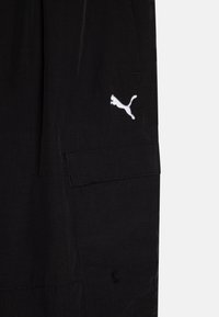 Juodos šortai iš lengvos medžiagos su elegantišku dizainu. Yra baltas išsiuvinėtas logotipas ir šoninės kišenės detalės.