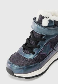Sneaker de cano alto com um acabamento brilhante em roxo e azul, atacadores pretos, um detalhe em forma de estrela e um punho fofinho branco. Sola de borracha.