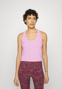 Top de alças sem mangas rosa com decote redondo, combinado com leggings de cintura alta com padrão de animal em rosa escuro e preto.