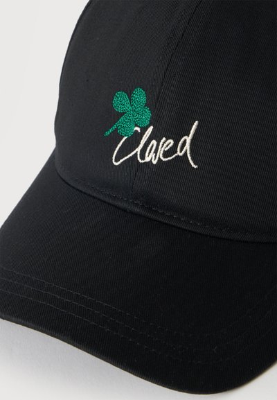 Casquette de baseball noire avec un trèfle à quatre feuilles brodé en vert et le mot "Loved" cousu en fil blanc sur le panneau avant.