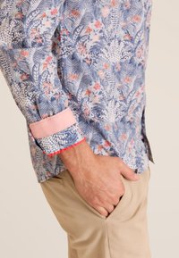 Bloemmotief overhemd in blauw, wit en roze. Heeft lange mouwen, roze manchetten en een getailleerde pasvorm met een zachte textuur.
