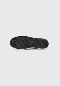 Black rubber sneaker sole with a zigzag tread pattern, white midsole, and a smooth pink upper edge. Minimalistic design, no visible branding.