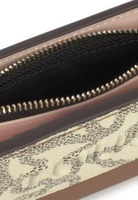 Billetera con cierre tipo zip que presenta un exterior texturizado en color beige con un patrón negro, forro rosa y herrajes dorados en el zipper. El interior incluye un bolsillo de tela negra.