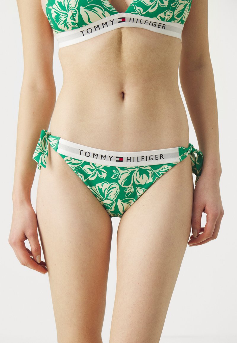 Grønt blomster bikini med V-hals bralette og sløyfeaccent på hoften. Har en hvit midjebånd med "TOMMY HILFIGER" logo.