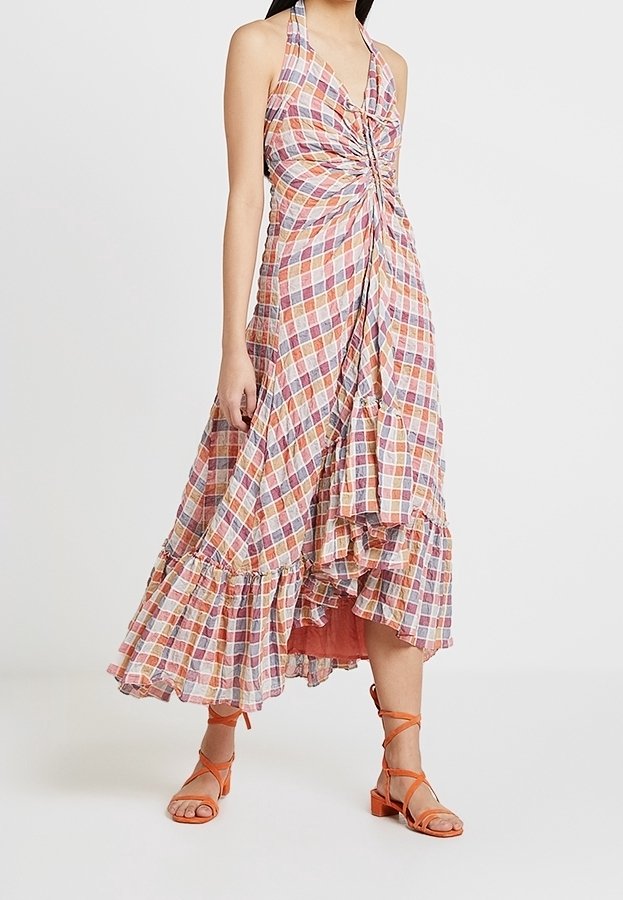Halter-neck klänning med en vriden front, lager-på-lager fåll, färggård rutigt mönster och en flödande silhuett. Kombinerad med orange remsandaler.