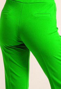 Pantalon ajusté vert avec une texture lisse et une coupe slim, doté de deux poches arrière et d'un design droit.