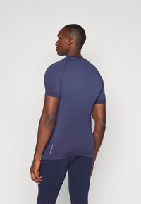 Mørkeblå kortermet treningsskjorte med tekstur og god passform, kombinert med mørkeblå leggings for et koordinert utseende.