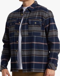 Camisa de franela a cuadros en azul marino con líneas blancas y marrones, que presenta dos bolsillos en el pecho, cierres de botones y mangas largas con puños de botón.
