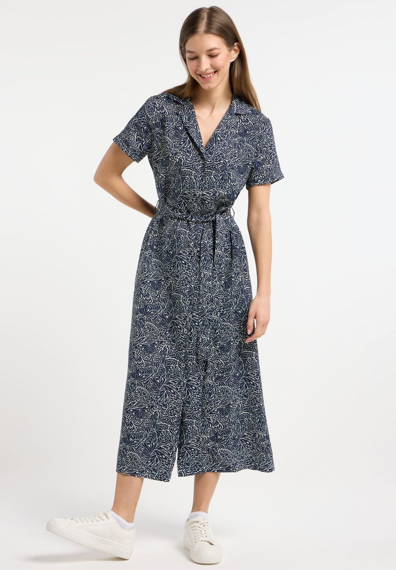 Blumendruck-Midikleid mit kurzen Ärmeln, Knopfverschluss vorne, Taillengürtel, in Navyblau und Weiß. Kombiniert mit weißen Sneakers. Weicher Stoff.