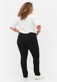 Black denim jeans with a fitted design, five pockets, and a mid-rise waist, paired with a white ribbed short-sleeve top.