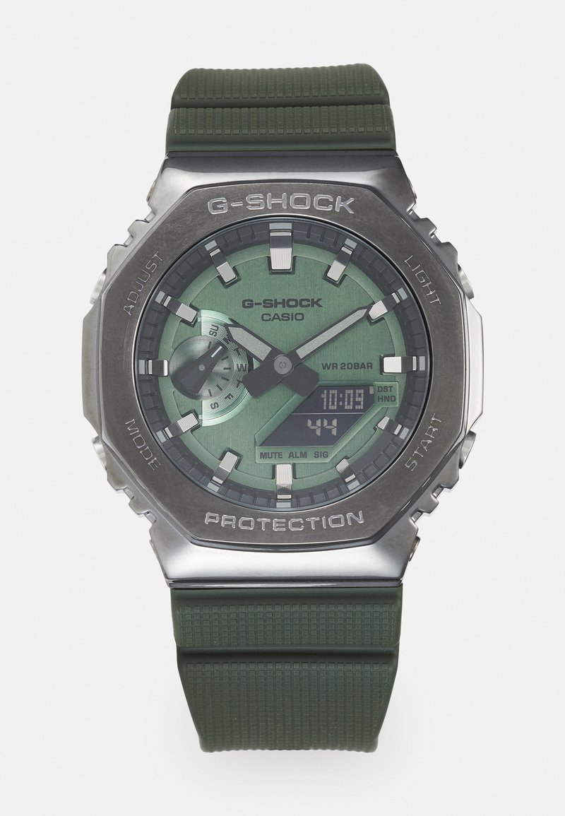 G-SHOCK watch with a green digital and analog display, stainless steel case, and textured dark green rubber strap. Water resistant to 20 bars.