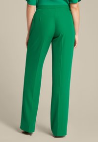 Pantaloni verdi su misura con una texture liscia, dotati di una vita aderente e gambe larghe e dritte. Il design include cuciture posteriori sottili.