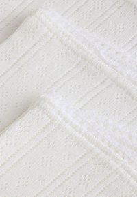 White textured towels with a ribbed pattern and soft, fluffy edges. Fabric is lightweight and absorbent, providing comfort and usability.
